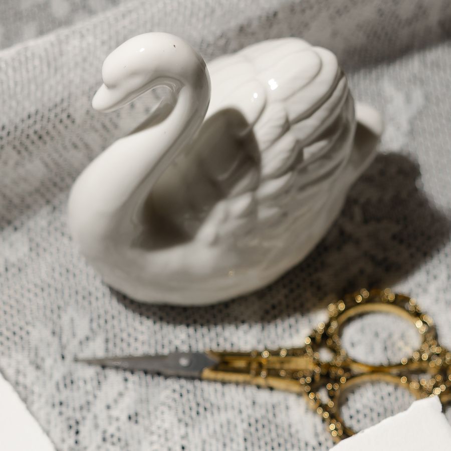 Ceramic swan and gold scissors on lace