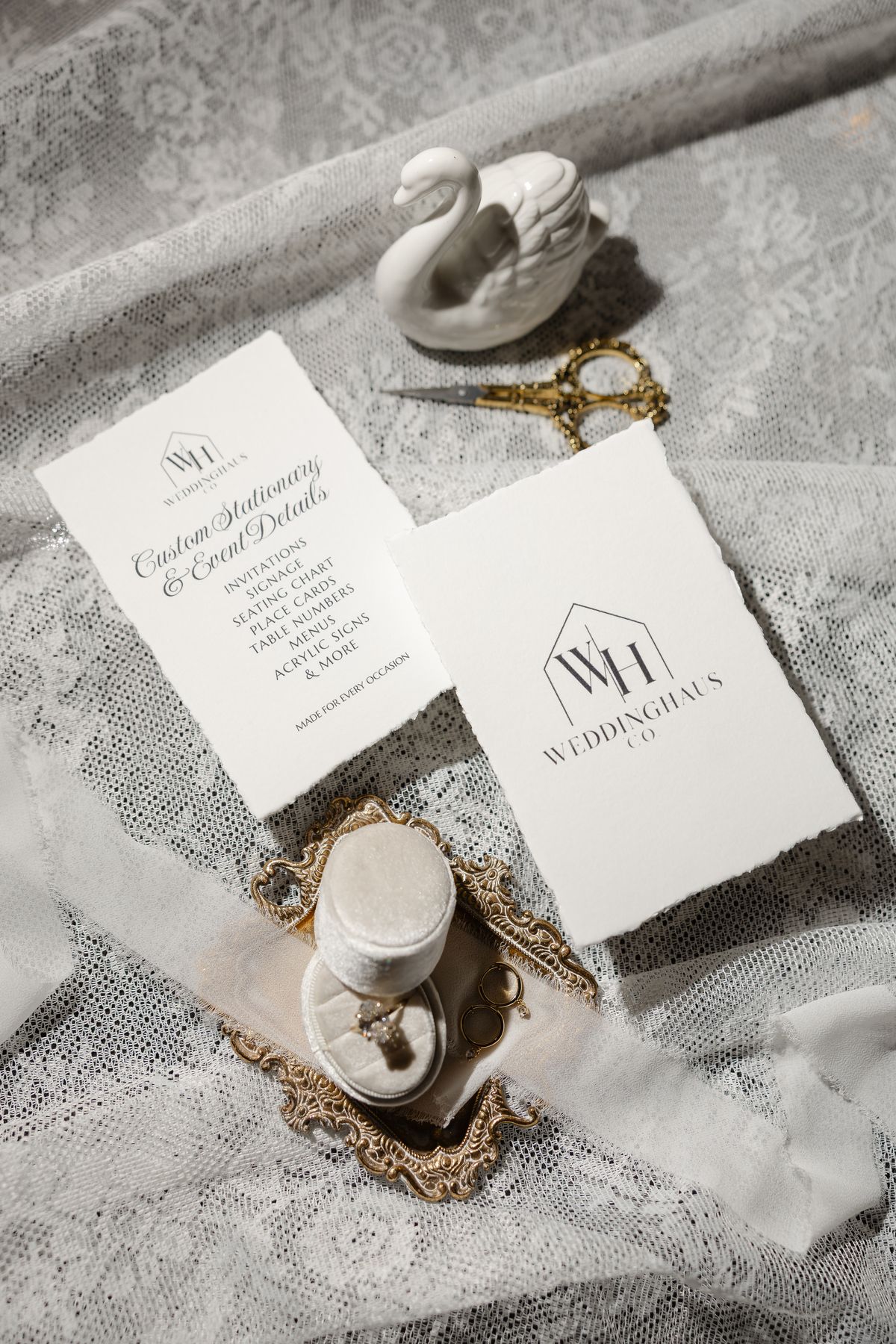 Two WeddingHaus Co. cards beside a ceramic swan and a velvet ring box